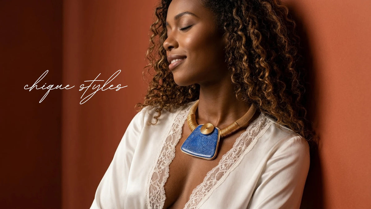 Model wearing a gold collar necklace with a blue stone pendant over a cream lace blouse